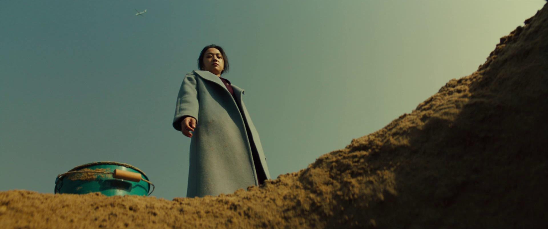 Song Seo-rae looks down into a hole in the sand.