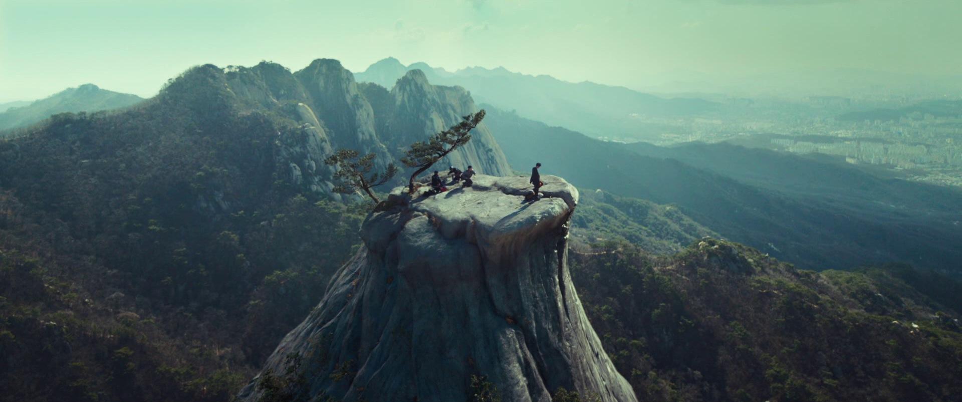 Men stand atop a large, pillar-like mountain.